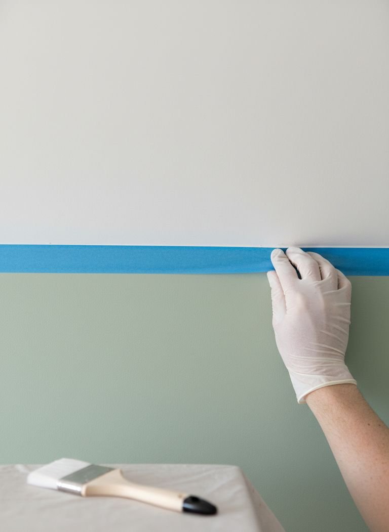 Color Capping: 5 Secret Ways to Achieve a Perfect Look 3 A DIY painter carefully cutting in the edge of a ceiling with a dark blue paint, demonstrating the color capping technique in progress.
